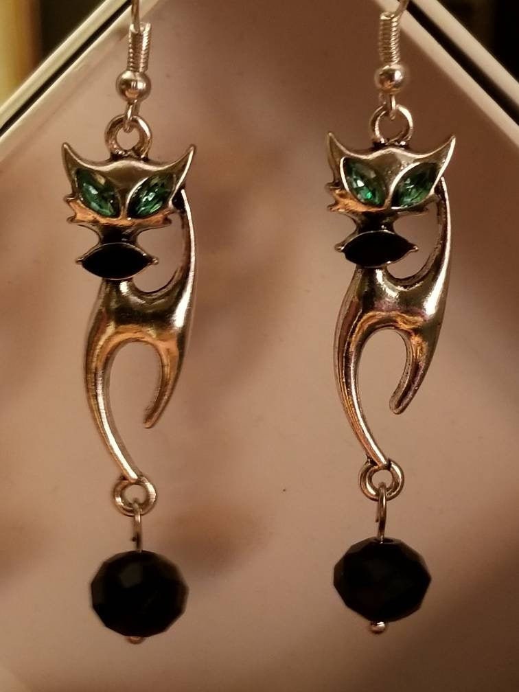 Charming 1950's Siamese Cat earrings. These silver dangly earrings feature green eyes & black bowtie on an iconic vintage siamese cat.